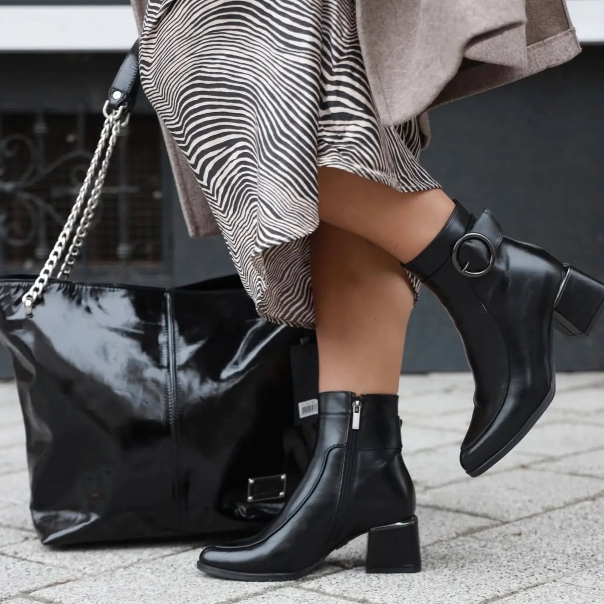 Black leather ankle boots with block heels and zipper, worn with zebra print skirt and black patent bag