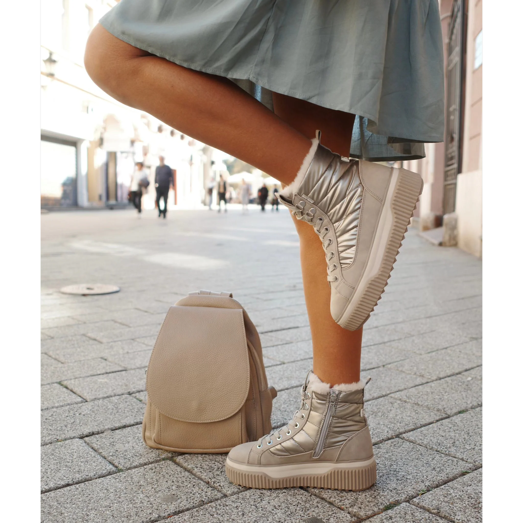 Taupe Tamaris Desert ankle boots with zip and fur lining worn on street with taupe backpack
